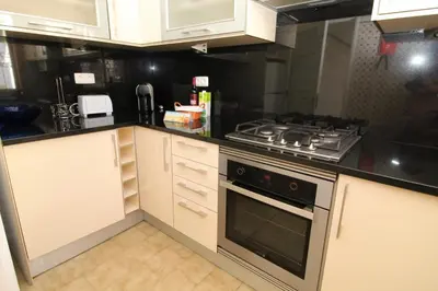 a kitchen with white cabinets and a stove top oven at Apartamento 53A São Rafael T2 duplex - Albufeira, Algarve in Albufeira
