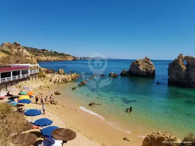 a beach with umbrellas and people in the water at Apartamento 53A São Rafael T2 duplex - Albufeira, Algarve in Albufeira
