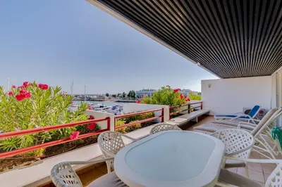 a balcony with chairs and a white table and a whiteboard at São Vicente - 1Br - Facing to Marina in Quarteira