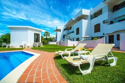 a villa with a swimming pool and chairs next to a house at 2 Bed Ground Floor Apartment In Vilamoura in Vilamoura