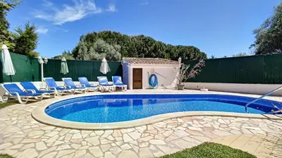 a swimming pool with chairs and a fence at Villa Palmeira Galé Beach in Albufeira