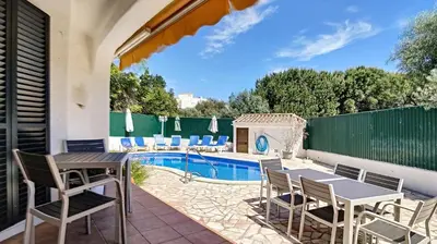 a patio with a table and chairs next to a swimming pool at Villa Palmeira Galé Beach in Albufeira