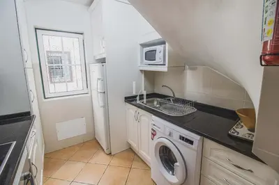 a small kitchen with a washing machine and a microwave at Old Village & Prestige in Vilamoura