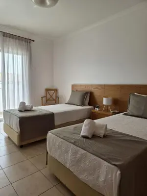 a bedroom with two beds and a balcony with the ocean at Albufeira Mar Vilas in Albufeira