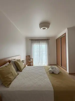 a bedroom with a large bed with two blue pillows at Albufeira Mar Vilas in Albufeira
