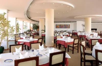 a dining room with tables and chairs with red tablecloths at Hotel Apartamento Paraiso De Albufeira in Albufeira