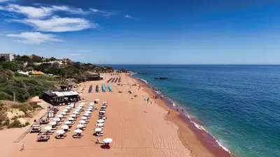 a beach with umbrellas and people on the beach at Hotel Apartamento Paraiso De Albufeira in Albufeira