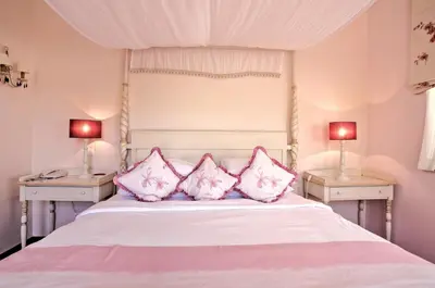 a bedroom with a white bed with pink pillows at Quinta Jacintina - My Secret Garden Hotel in Vale do Lobo