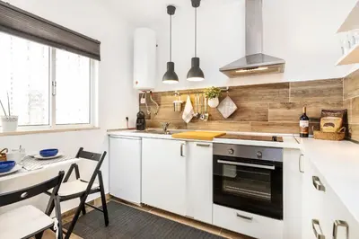 a kitchen with white cabinets and a table and a sink at Modern Pool Apartment, Vilamoura in Quarteira