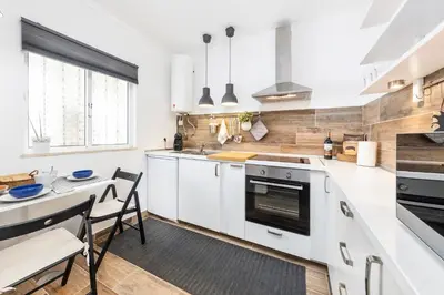 a kitchen with white cabinets and a table and chairs at Modern Pool Apartment, Vilamoura in Quarteira