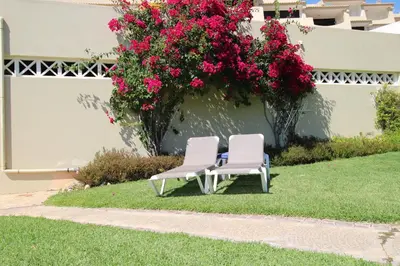 two chairs sitting on the grass in front of a building with flowers at magnifique appartement sur la plage ... in Albufeira