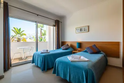 a hotel room with two beds and a balcony at Apartamentos Turisticos Monte da Vinha II in Albufeira