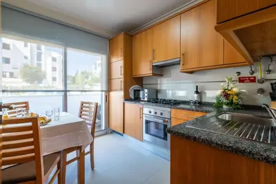 a kitchen with wooden cabinets and a table with a counter top at Apartamentos Turisticos Monte da Vinha II in Albufeira