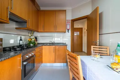a kitchen with wooden cabinets and a table with a white table cloth at Apartamentos Turisticos Monte da Vinha II in Albufeira