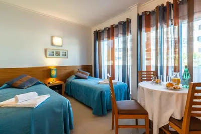 a hotel room with two beds and a table and chairs at Apartamentos Turisticos Monte da Vinha II in Albufeira