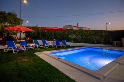 a swimming pool with chairs and umbrellas in a yard at LOTUS VILLA, Albufeira in Albufeira