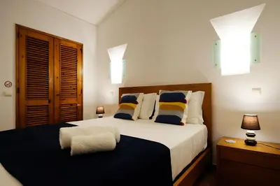 a bedroom with a large bed with blue and yellow pillows at LOTUS VILLA, Albufeira in Albufeira