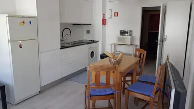 a kitchen with a table and chairs and a kitchen with a refrigerator at Apartment Girasol Front Beach Quarteira Algarve in Quarteira