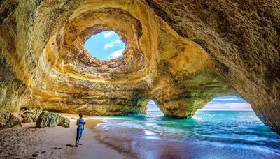 a man standing on a beach in front of a cave at Welcoming apartment in Albufeira 60 m² with shared pool in Albufeira