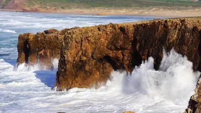 a large cliff in the ocean with water crashing onto it at Charming Apartment in Albufeira - 60 m² with pool & view in Albufeira
