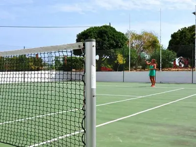 a woman is playing tennis on a tennis court at magnifique maison en resort près des plages in Albufeira
