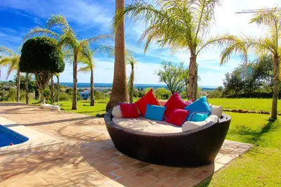 a couch with colorful pillows sitting in a garden at FARMHOUSE CASA DA AVÓ in Loulé