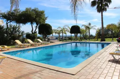a swimming pool with chairs and palm trees at FARMHOUSE CASA DA AVÓ in Loulé