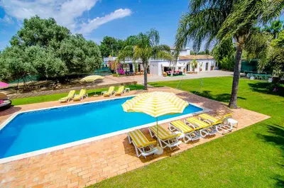 a swimming pool with lounge chairs and an umbrella at FARMHOUSE CASA DA AVÓ in Loulé