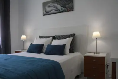 a bedroom with a bed with blue sheets and pillows at Apartamento com Piscina em Albufeira, Praia da Oura in Albufeira