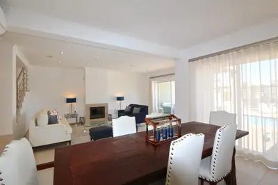 a living room with a wooden table and white chairs at Villa Gustas 150 - Clever Details in Vilamoura