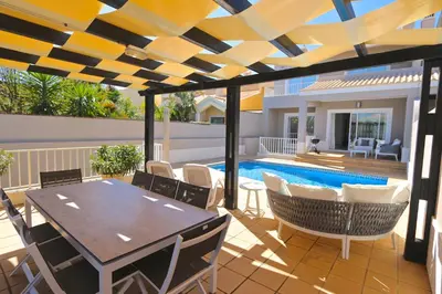 a patio with a table and chairs and a swimming pool at Villa Gustas 150 - Clever Details in Vilamoura
