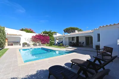a villa with a swimming pool and two lawn chairs at Villa Caroline 3 - Clever Details in Vilamoura