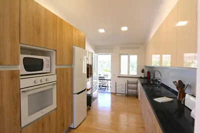 a kitchen with white appliances and wooden cabinets at Villa Caroline 3 - Clever Details in Vilamoura