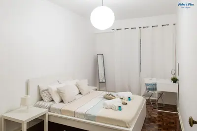 a white bedroom with a bed and a chair at Palma's Place in Faro