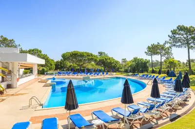 a swimming pool with lounge chairs and umbrellas at Victory Village T1 & Mezzanine in Quinta do Lago