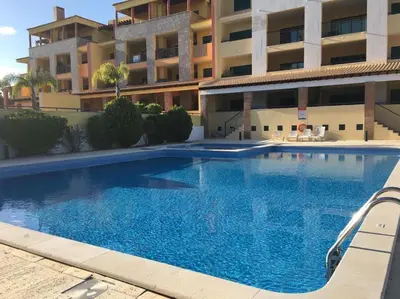 a large blue swimming pool in front of a building at Apartamento golf-mar in Vilamoura