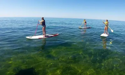 two people are standing on paddle boards in the water at Luxurious T2 apartment, Olhos Dagua in Albufeira