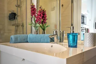 a bathroom sink with a blue glass and flowers on it at Blue Barqueta Studio in Faro
