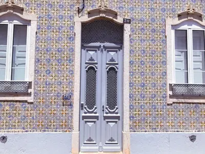a gray door on a building with a tile wall at Terrace Barqueta Studio in Faro