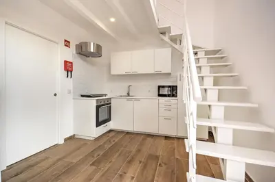 a kitchen with white cabinets and a spiral staircase at Terrace Barqueta Studio in Faro