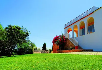 a white house with a staircase next to a lawn at Villa Esmeralda in Albufeira