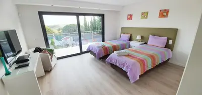 a bedroom with two beds and a tv and a balcony at Villa Margarida by Laranjal Rentals in Albufeira