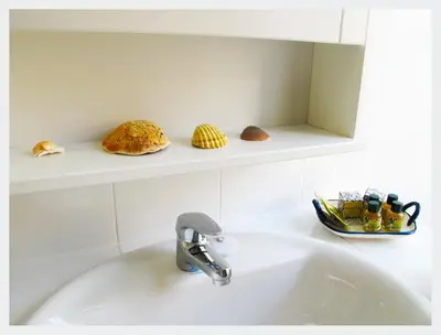 a bathroom sink with a faucet and some shells at Senhor Gigi in Faro