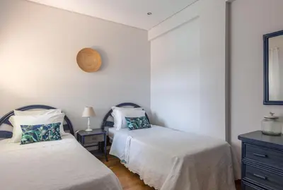a bedroom with two beds and a clock on the wall at SeaShell Apartment by Atlantic Places in Albufeira