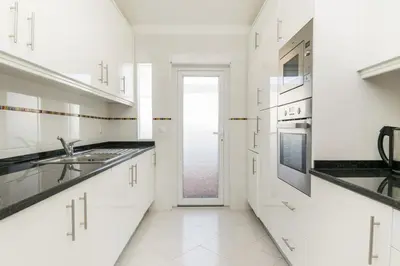 a white kitchen with a sink and a door at Great S.Rafael Aprt. walking distance to the beach in Albufeira