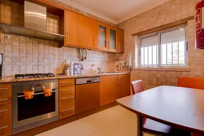 a kitchen with wooden cabinets and a table in it at Avelãs - Modern apartment - Vilamoura in Vilamoura