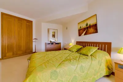 a bedroom with a large bed and a wooden cabinet at Avelãs - Modern apartment - Vilamoura in Vilamoura