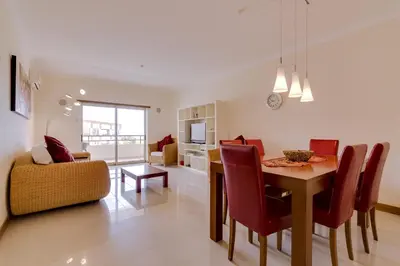 a dining room and living room with a table and chairs at Avelãs - Modern apartment - Vilamoura in Vilamoura