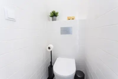 a white bathroom with a toilet and a plant at Alameda Exclusive House in Faro