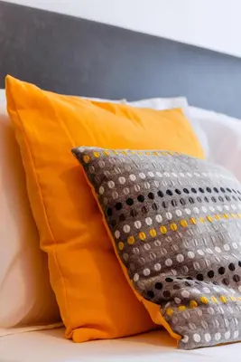 an orange and gray pillow on a bed at Quinta do Paiva - Jardins do Vale in Roja- Pé
